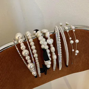 Collection of French vintage pearl and rhinestone headbands on a brown corduroy display