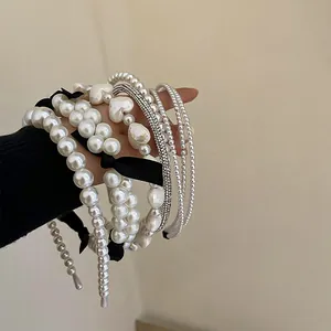 Detailed view of elegant French style white pearl and bow headbands held on a hand