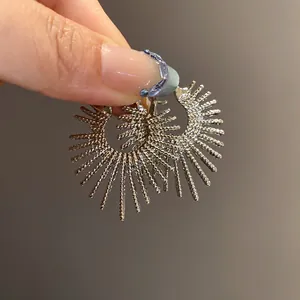 Detaillierte Makroansicht silberner Creolen im eleganten Feuerwerk-Sonnenschliff-Design.