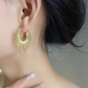 Nahaufnahme des unregelmäßigen Sonnenstrahl-Feuerwerk-Designs der goldenen Ohrringe