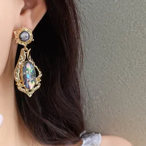 Close-up of vintage gold drop earrings with iridescent shell inlay on Asian model
