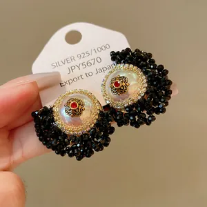 Macro detail of French vintage earrings with pearls, red crystals, and black bead clusters.