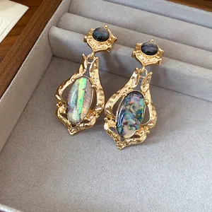 Close-up of vintage gold dangle earrings with colorful abalone shell inlays
