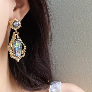 Detailed view of vintage golden earrings with iridescent shell inlay worn on a model's ear