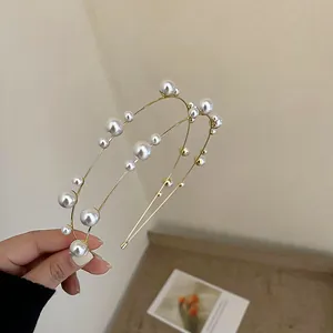 Detail view of a double-layered gold headband with elegant white pearls