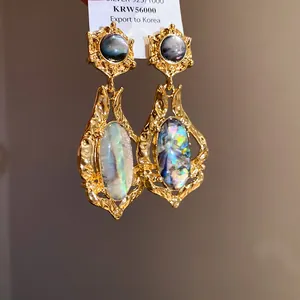Macro view of vintage gold hammered earrings with shimmering colorful shell inlays