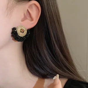 Detail view of French vintage floral earrings with black crystals and gold-tone finish