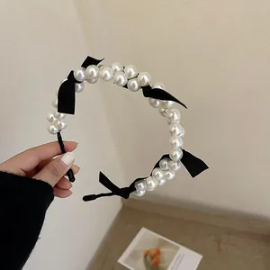Close-up of elegant French vintage headband with white pearls and black bows.