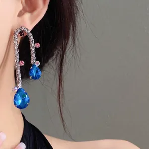 Elegant silver woven drop earrings with vibrant blue teardrop-shaped rhinestones.