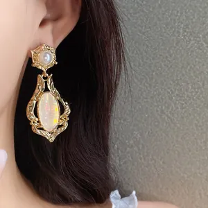 Close-up of vintage gold earrings with iridescent oval stones and pearl details