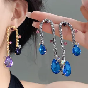 Detail view of woven metal water drop earrings with vibrant blue pear-cut crystals