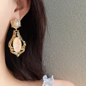 Close-up detail of elegant vintage gold earrings with pearl and oval iridescent shell inlay