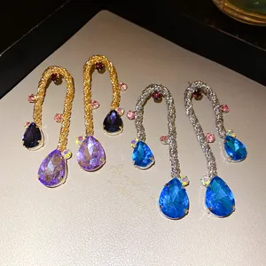 Detailed macro view of vintage style woven drop earrings with blue and purple crystals.