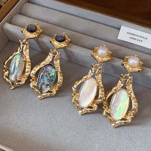 Detailed view of vintage gold-tone oval shell earrings with hammered metal texture