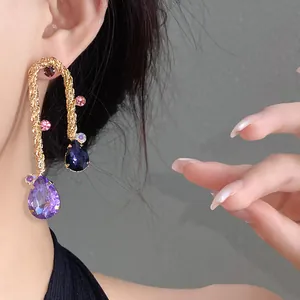 Detailed view of gold braided earrings with purple teardrop crystals and vintage style.