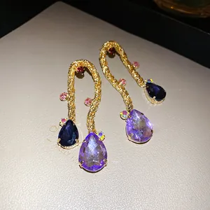 Close-up macro view of vintage braided gold earrings with purple teardrop crystals.