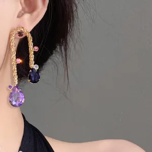 Detailed close-up of a vintage-style gold braided earring with colorful water-drop gems
