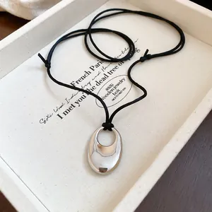 Elegant minimalist silver-tone oval hollow pendant on a stylish adjustable black cord