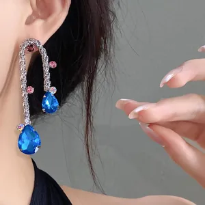Macro view of vintage woven earrings with blue teardrop crystals and colorful rhinestones.