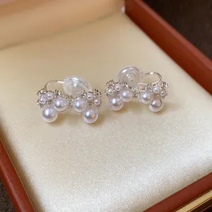 Close-up view of French zircon and pearl bow-shaped clip-on earrings in a box