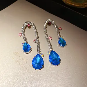 Close-up of vintage woven silver earrings featuring vibrant blue water drop stones.