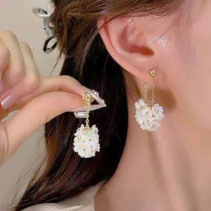Dettaglio dei fiori di perla bianca su eleganti orecchini a catena d'oro indossati