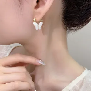 Dettaglio di un elegante orecchino a farfalla bianco con cerchio dorato sull'orecchio