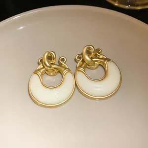Dettaglio macro di orecchini vintage placcati oro con elegante finitura in smalto crema