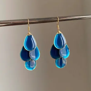 Detailed view of translucent blue teardrop oil-dripped earrings with gold hooks.