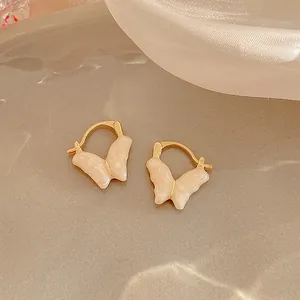 Elegante dettaglio ravvicinato di orecchini a cerchio dorati con farfalle crema