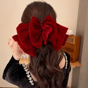 Gros nœud papillon en velours rouge plissé sur longs cheveux bruns ondulés