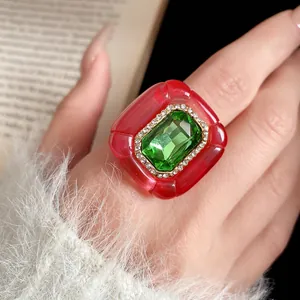 Close-up of vintage red resin ring with green gemstone and pleated texture