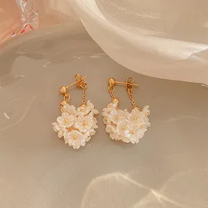 Dettaglio di eleganti orecchini a grappolo di fiori di perla bianca con catene d'oro.