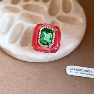 Detail view of a vintage red resin ring featuring a large emerald green center gemstone.