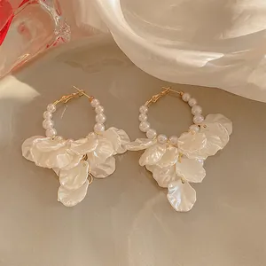 Eleganti orecchini a cerchio dorati con perle bianche e petali traslucidi.
