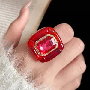 Macro view of vintage red resin ring with sparkling rhinestone border and pleated texture