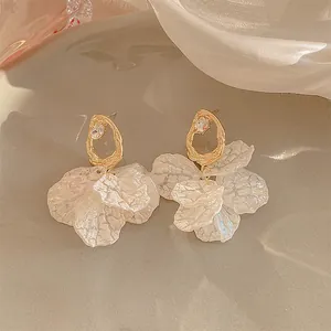 Dettaglio di eleganti orecchini a fiore con petali iridescenti e aghi in argento dorato