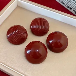 Vintage burgundy round stud earrings with smooth and ribbed textures displayed in a tray