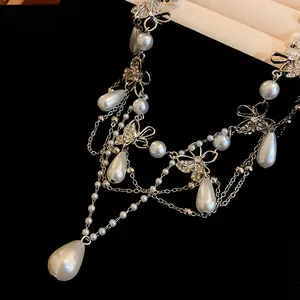 Detailed close-up of elegant butterfly necklace with silver chains and white teardrop pearls