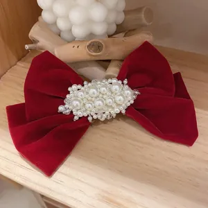 Vue détaillée d'une barrette noeud en velours rouge avec perles élégantes sur bois