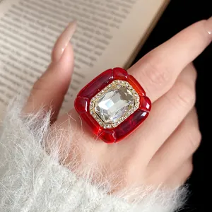Close-up detail of vintage red resin ring with large faceted crystal and rhinestone border