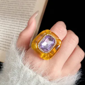 Detailed macro shot of a chunky yellow resin ring with a purple gemstone.