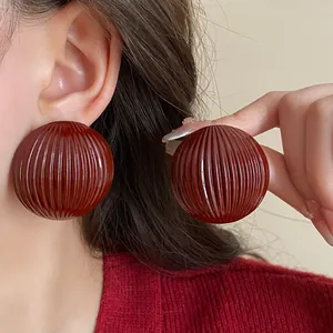 Detail view of retro oversized round striped stud earrings for women in deep red color