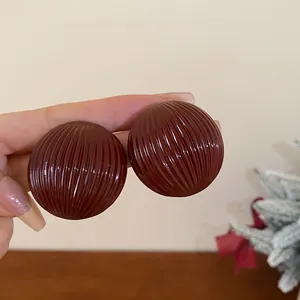Close-up of oversized burgundy round ribbed earrings with vintage texture