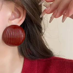 Close-up detail of a large vintage burgundy striped round stud earring for women