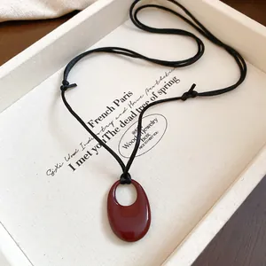 Reddish-brown oval ceramic pendant on black adjustable cord for a niche retro style