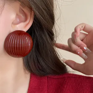 Detailed view of large dark red geometric round striped earrings with retro design