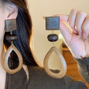 Close-up of retro geometric wooden drop earrings with hollow teardrop design