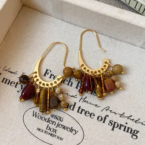 Detail view of vintage-inspired gold-plated earrings with colorful stone tassels