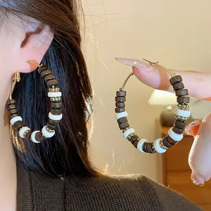 Close-up detail of retro wood and white beaded hoop earrings with gold accents